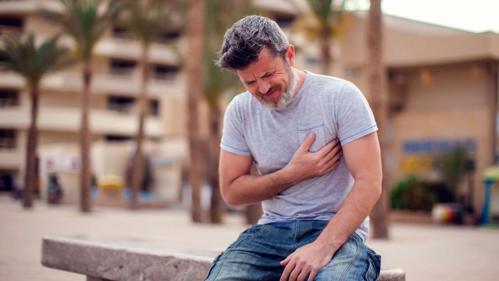 A man clutching his chest with his hand, showing signs of severe chest pain