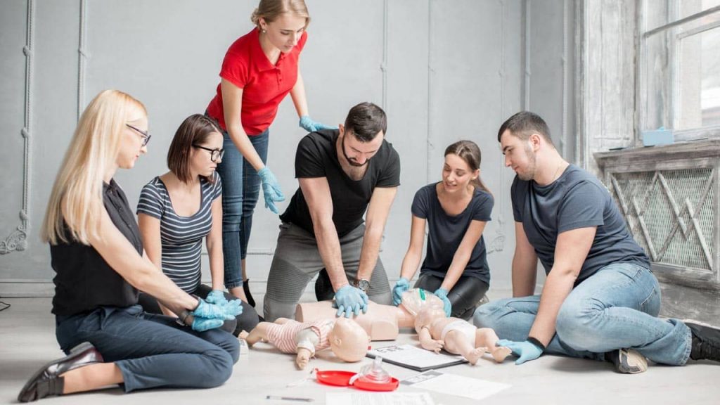 A group of people practicing CPR techniques on training mannequins during a first aid class