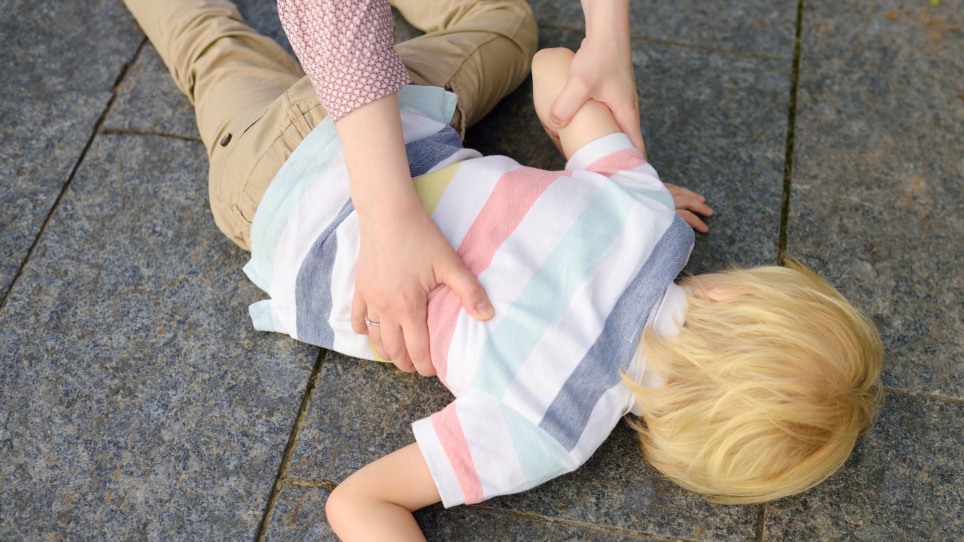 A children facing down to the floor, looks like he fell