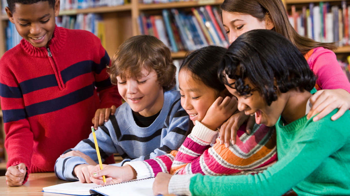 five kids gathered together and looking into a book