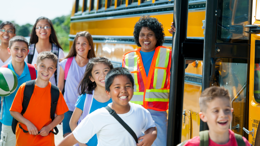 A group of kids getting on a school bus with an attendant.