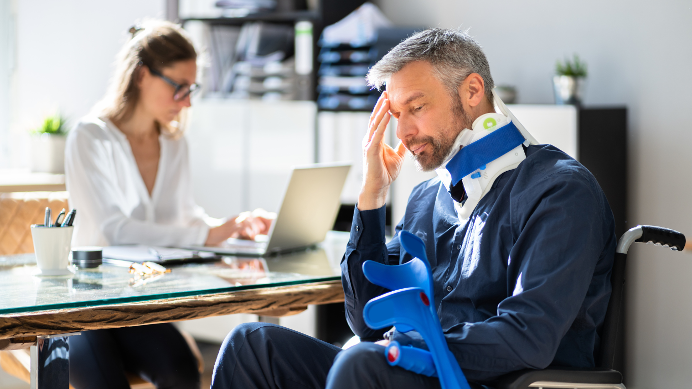 A man with a neck injury wearing a neck brace and sitting in an office.