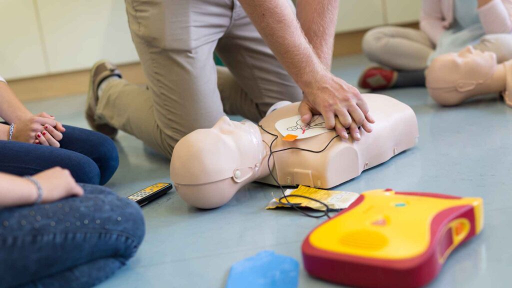 A person practicing CPR with an AED