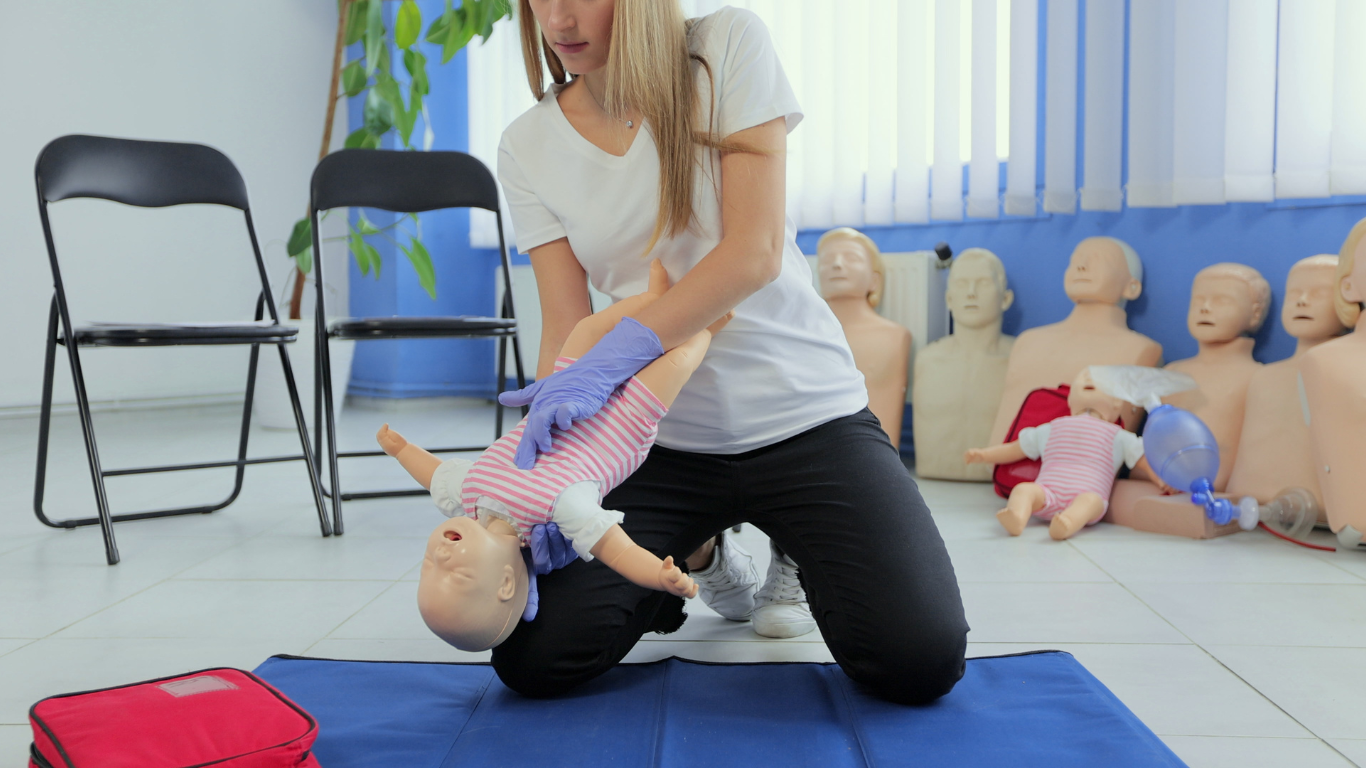 A lady performing CPR training on a baby mannequin 