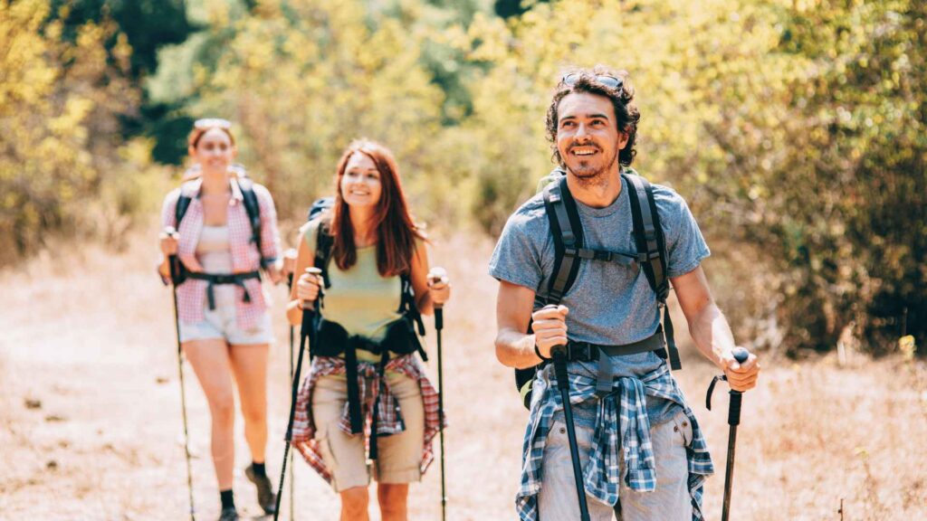 A group of three friends, one male and two females, enjoying a hike together.