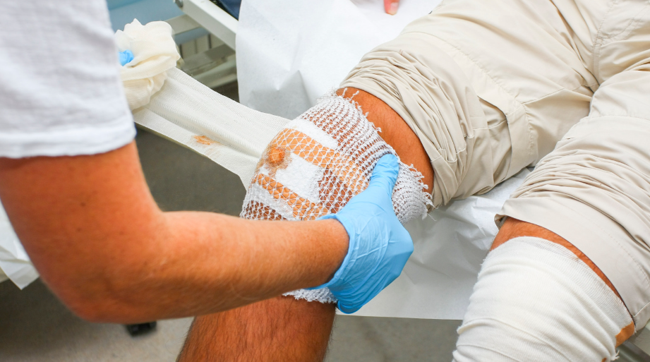 A first- aid professional applying dressing to a wound after cleaning it.