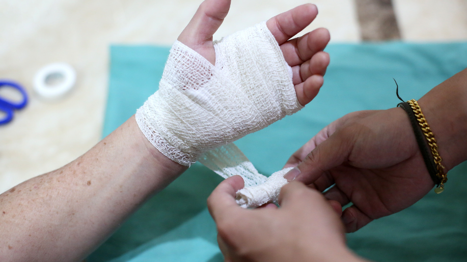 A first aid professional bandaging a wounded hand.