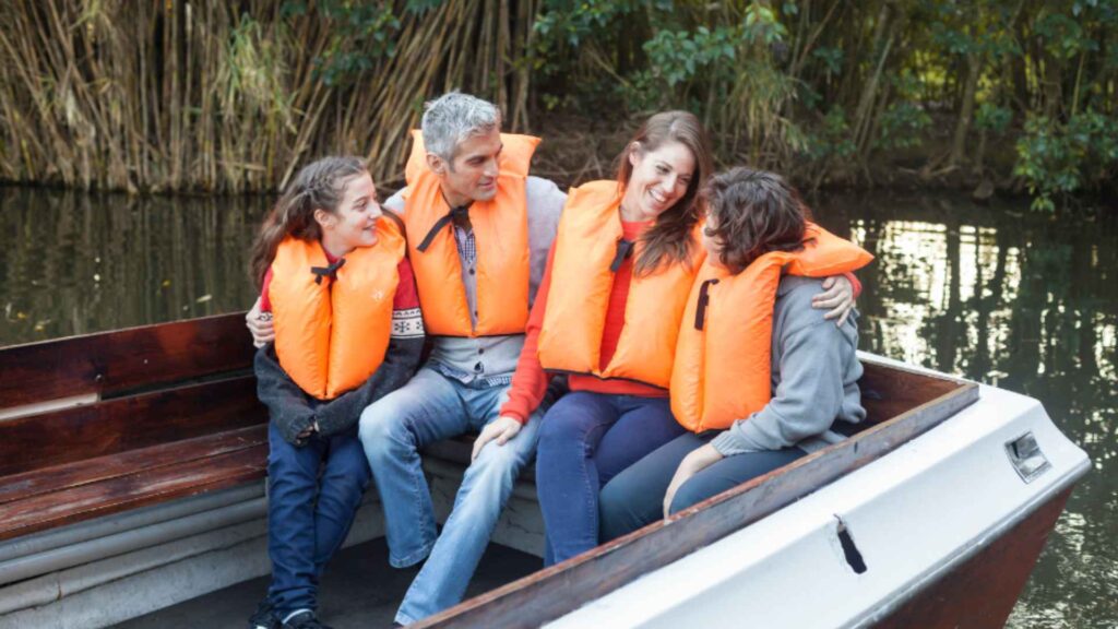 A family wearing PFDs enjoying boating in a lake.