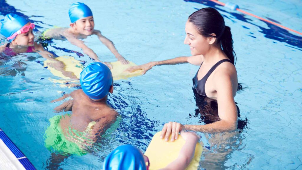 A trainer giving swimming lessons to children.