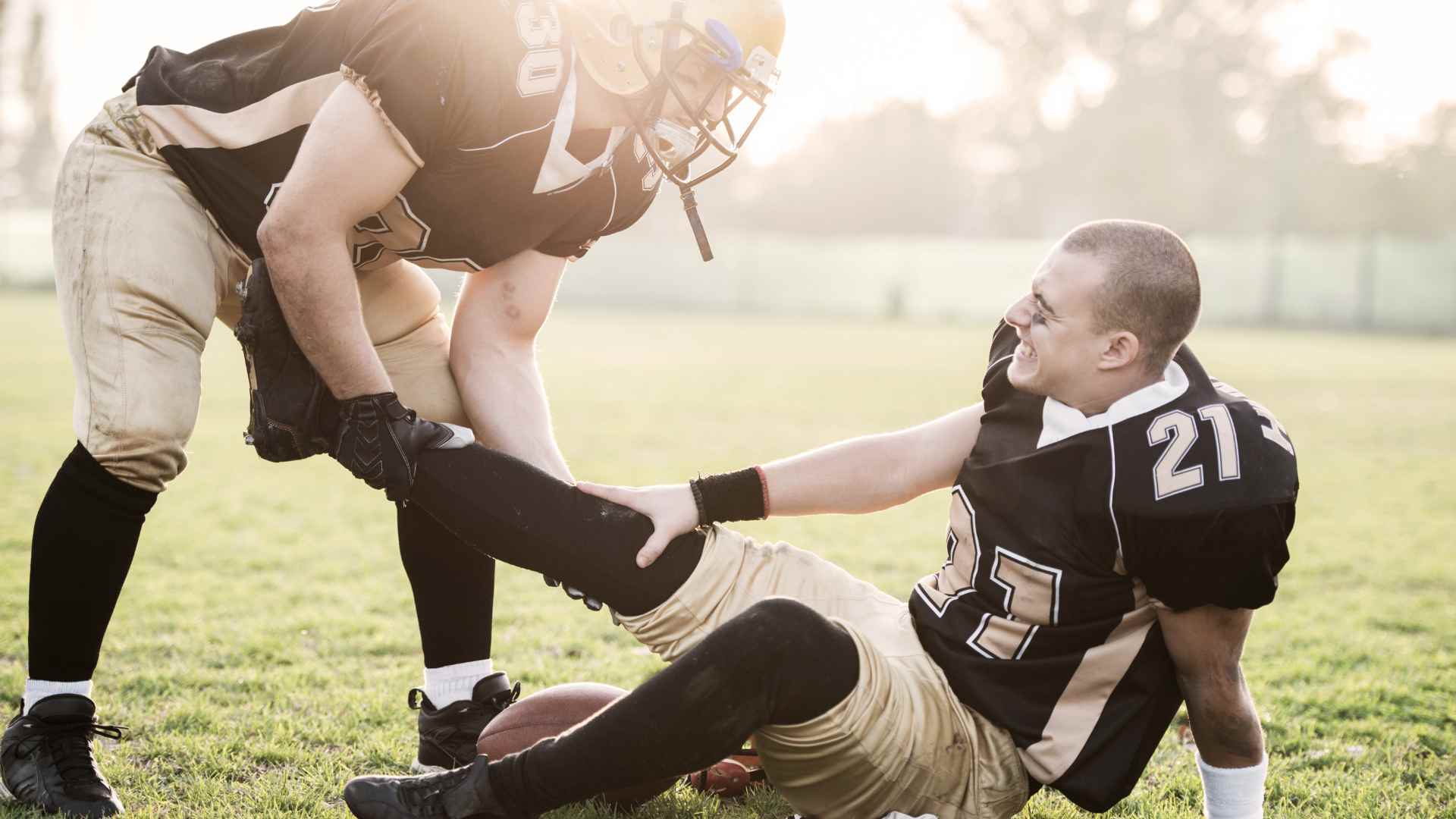 A player doing first aid in sports for an injured co-player on a soccer field.