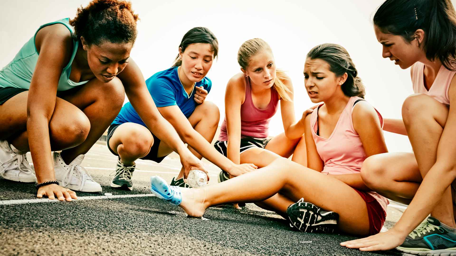 A young athlete injured and her friends providing her with first aid