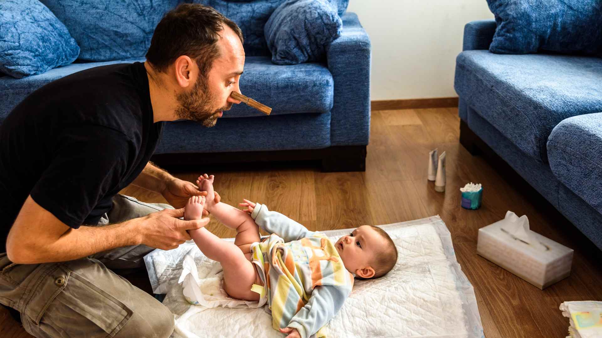 A father changing diaper of his son as a part of infant care.