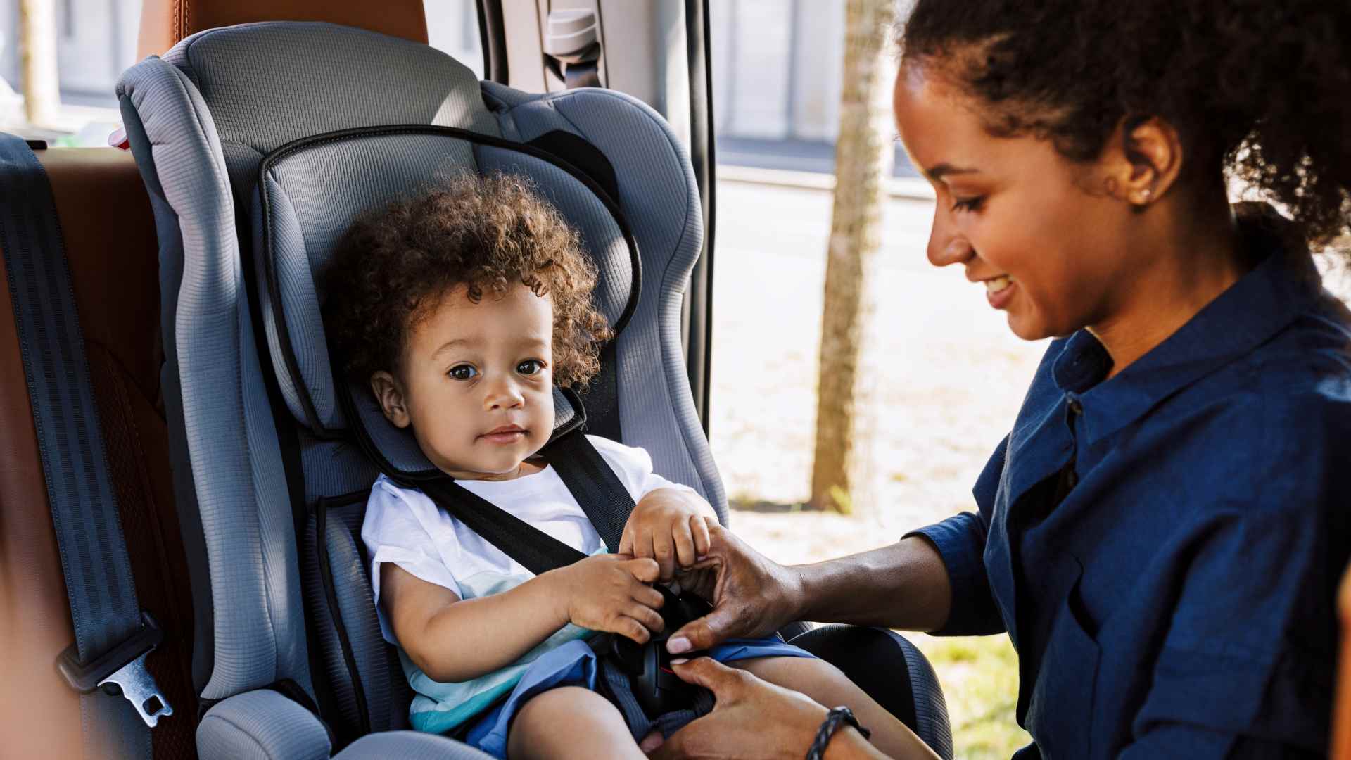 A mother safety putting her infant in a car with safety belt on as a part of infant care.