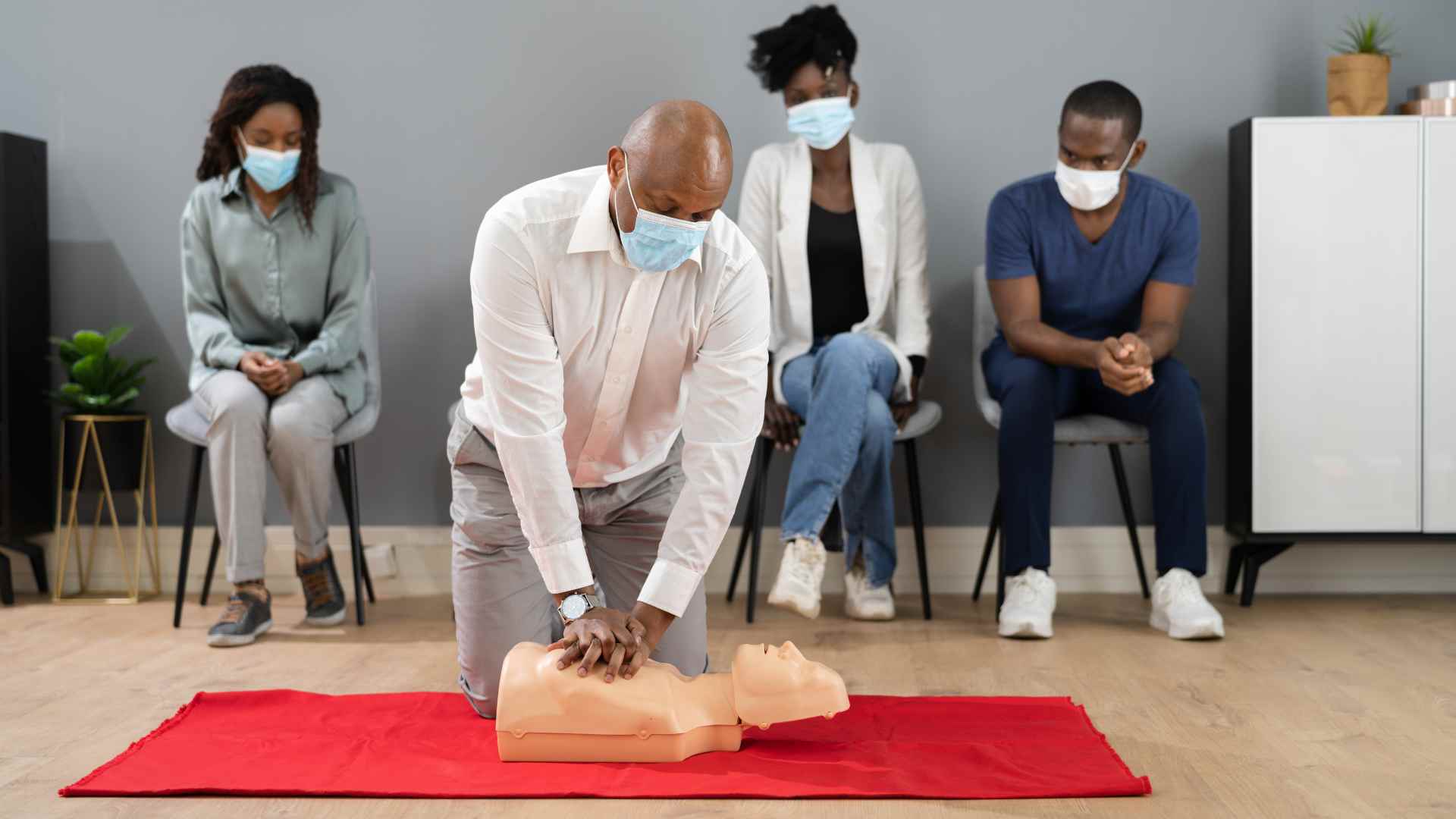 A group of people learning workplace first aid training.