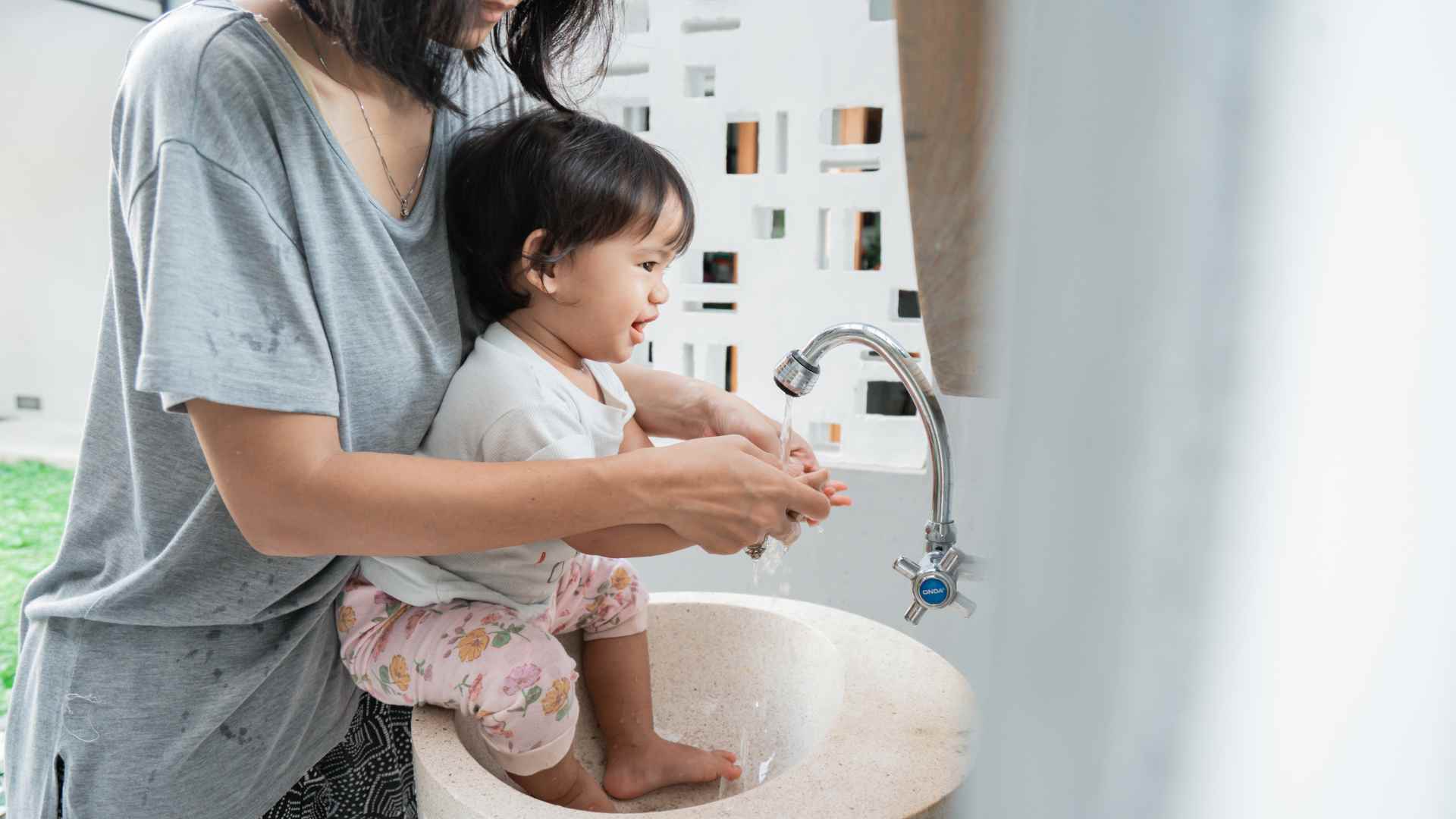 A mother teaching handwashing to his infant.