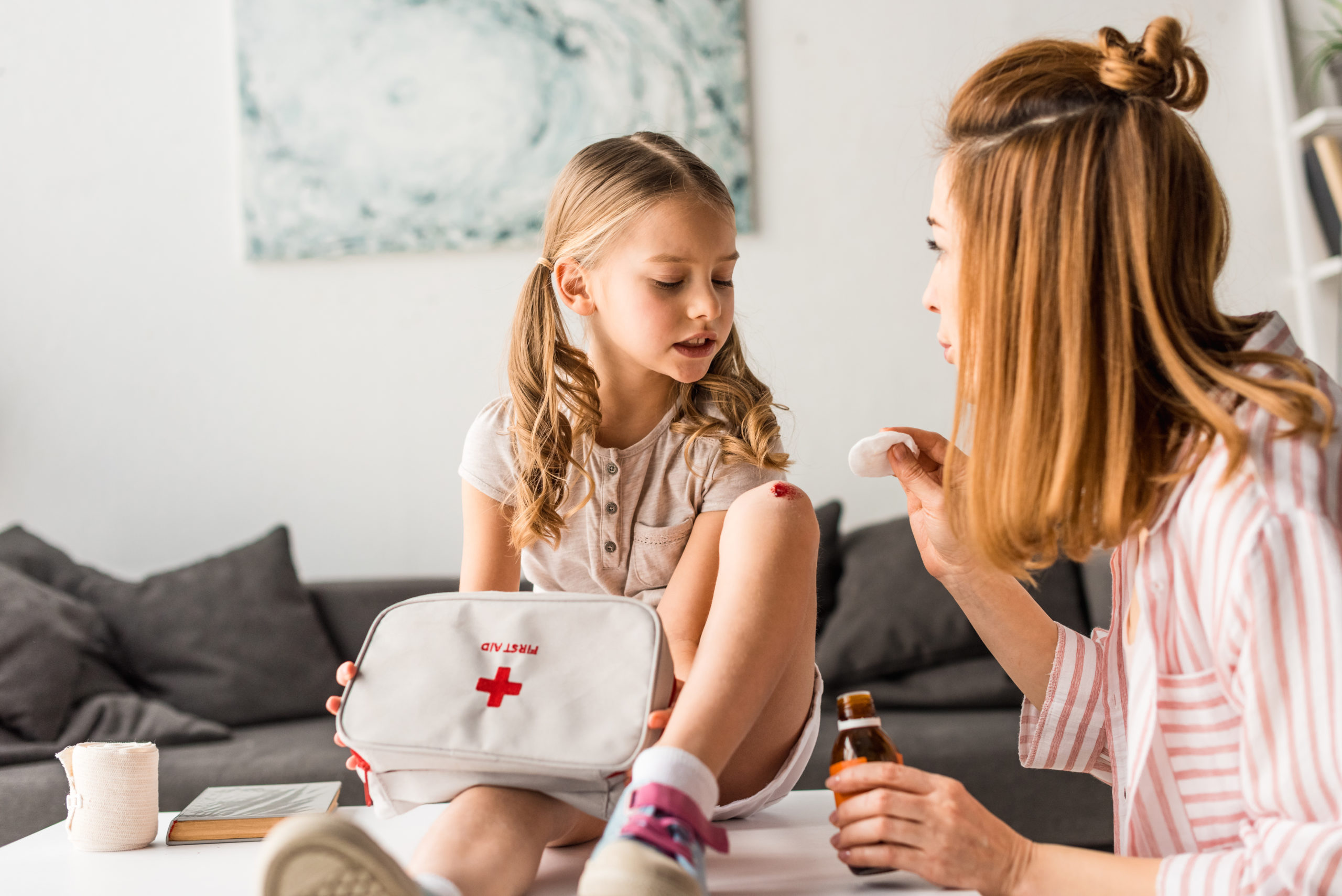 A mother practicing first aid skills on her daughter using a first aid kit.