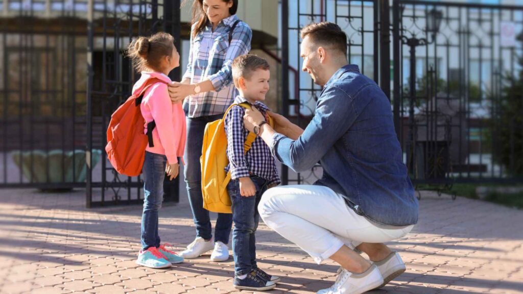 Parents preparing their children wearing backpacks going back to school.