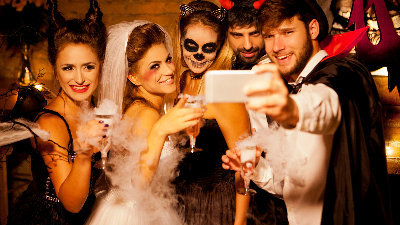 People taking a group picture using a phone in their halloween costumes.